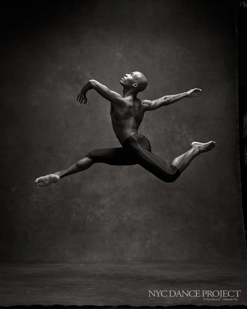 Jamal Callender leaping in a black-and-white studio photograph.